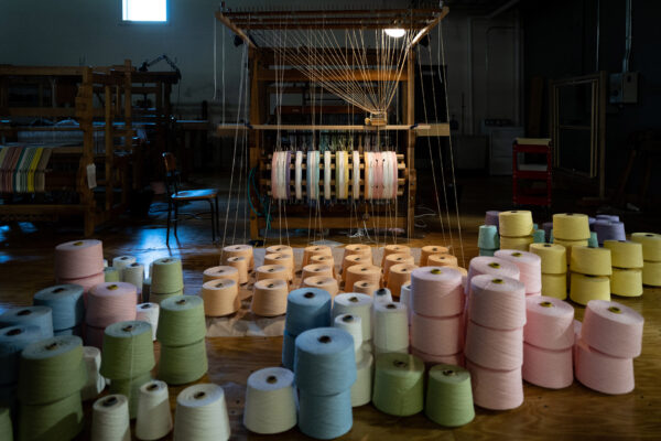 Spools of thread in front of a weaving loom
